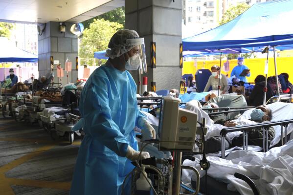FILE - Patients in hospital beds wait in a temporary holding area outside Caritas Medical Centre in Hong Kong on March 2, 2022. Some people are forced to wait outside the hospital due to it currently being overloaded with possible COVID-infected patients. The fast-spreading omicron variant is overwhelming Hong Kong, prompting mass testing, quarantines, supermarket panic-buying and a shortage of hospital beds. Even the morgues are overflowing, forcing authorities to store bodies in refrigerated shipping containers. (AP Photo/Kin Cheung, File)