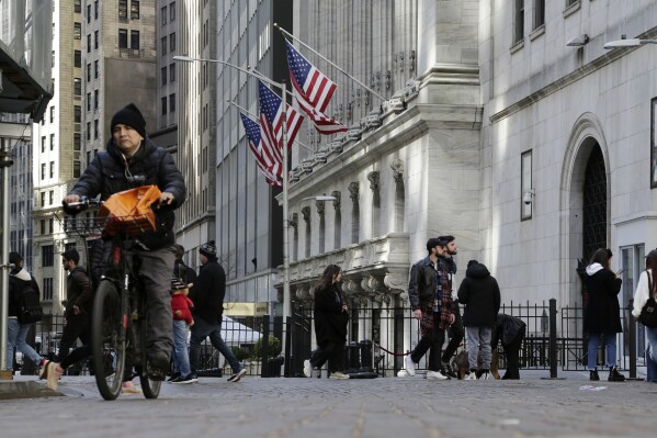 People pass the front of the New York Stock Exchange in New York, Tuesday, March 21, 2023. (AP Photo/Peter Morgan, File)