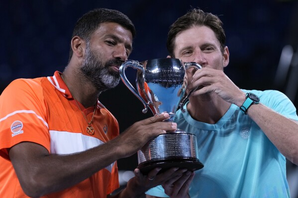 Rohan Bopanna, left, of India and Matthew Ebden of Australia pose with their trophy after defeating Simone Bolelli and Andrea Vavassori of Italy in the men's doubles final at the Australian Open tennis championships at Melbourne Park, Melbourne, Australia, Saturday, Jan. 27, 2024.(AP Photo/Alessandra Tarantino)