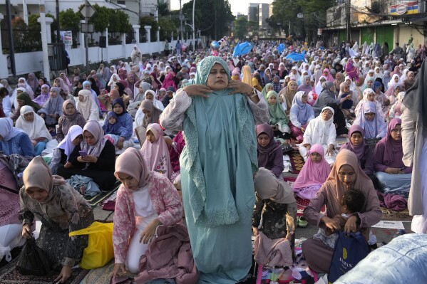 A Muslim woman dons her praying robe as she attends an Eid al-Fitr prayer marking the end of the holy fasting month of Ramadan in Jakarta, Indonesia, Wednesday, April 10, 2024. (AP Photo/Dita Alangkara)