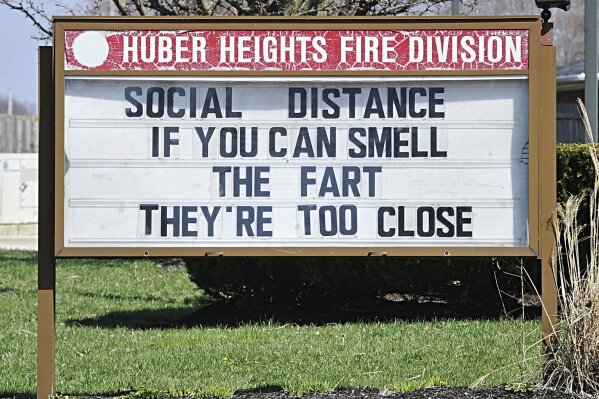 FILE - In this March, 25, 2020, file photo, a sign sits in front of the Huber Heights Fire Division in Huber Heights, Ohio. It may be a little awkward, but humor is helping people around the planet cope with the fear and anxiety the coronavirus pandemic has unleashed. (Marshall Gorby/Dayton Daily News via AP)