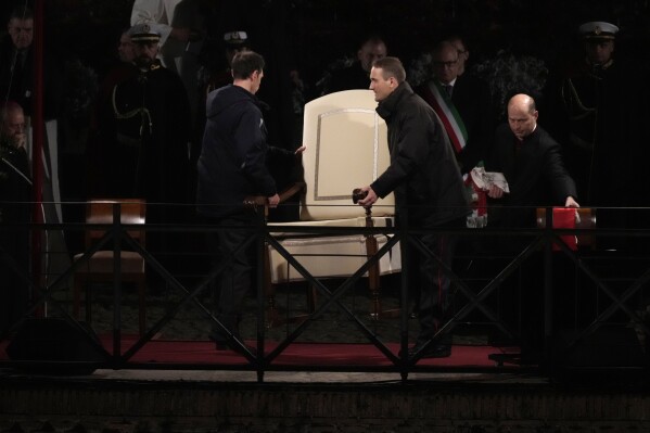 Vatican ushers carry Pope Francis chair prior to the start of the Via Crucis (Way of the Cross) at the Colosseum on Good Friday, in Rome, Friday, March 29, 2024. (AP Photo/Gregorio Borgia)