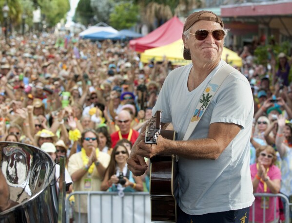 FILE- In this Nov. 4, 2011, file photo released by the Florida Keys News Bureau, singer/songwriter Jimmy Buffett performs before fans on Duval Street in Key West, Fla. (Rob O'Neal/Florida Keys News Bureau via AP)