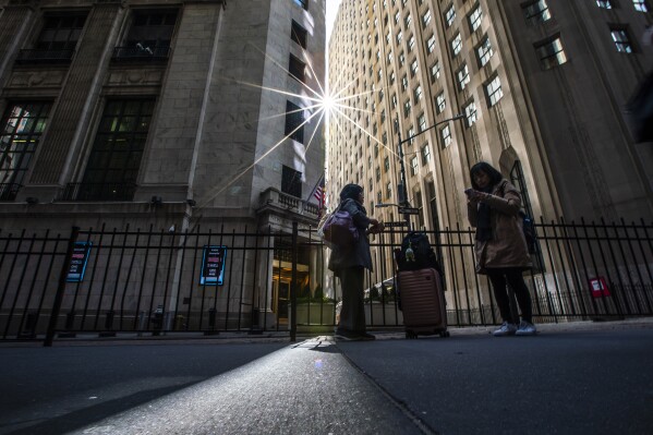 FILE - People pause near an entrance to the New York Stock Exchange in New York, March 19, 2024. (AP Photo/Eduardo Munoz Alvarez, File)