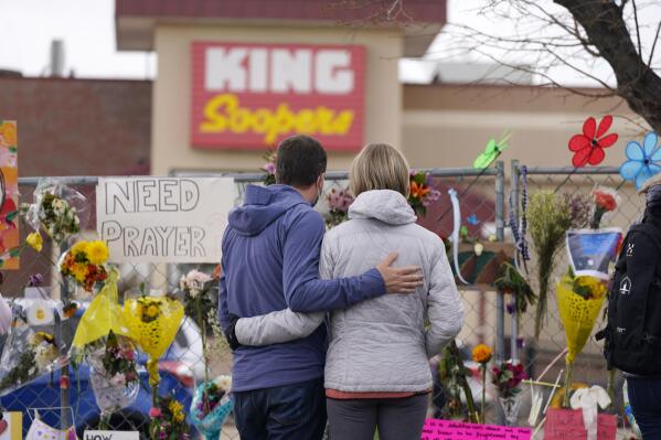 FILE - In this March 26, 2021, file photo, mourners walk the temporary fence line outside the parking lot of a King Soopers grocery store, the site of a mass shooting in Boulder, Colo. Colorado prosecutors have filed over 40 more felony charges against the man charged with killing 10 people at the Boulder supermarket last month — including allegations he used a large capacity magazine that had been banned by state lawmakers in 2013 in response to mass shootings. (AP Photo/David Zalubowski, File)