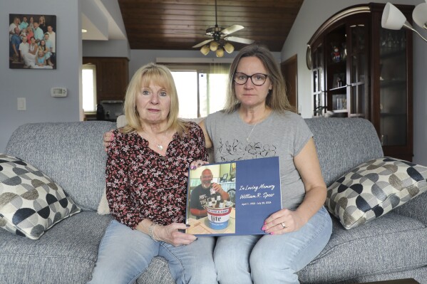 Boni Speer, left, and her daughter, Tracy Balhan, hold a photo of Bill Speer, Tracy’s father, in Aurora, Ill., on Friday, March 14, 2025. (Benjamin Thorp/WFYI Public Media via AP)
