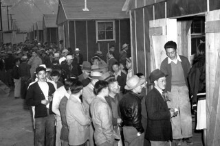 In this March 24, 1942 file photo Japanese citizens wait in line for their assigned homes at an alien reception center in Manzanar, Calif. Many were forced from their homes in Los Angeles by the U.S. Army. (AP Photo, file)