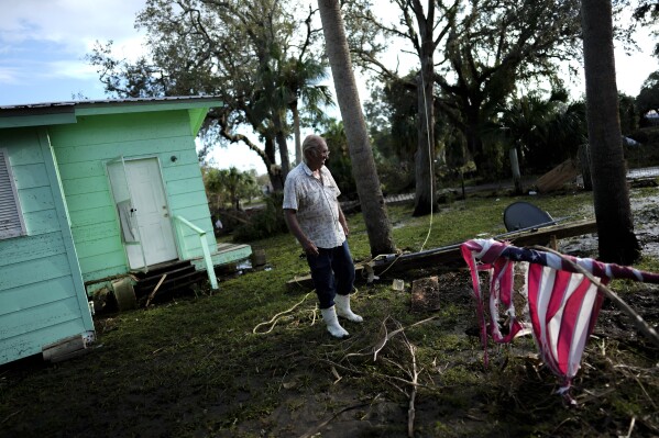 A storm tattered American flag lies wrapped around its downed pole in the front yard of Herman Neely, a retired corrections officer known by the nickname "Pork Chop," after storm surge from Hurricane Idalia shifted Neely's home from its blocks and punched holes through the inside walls, in Horseshoe Beach, Fla., Thursday, Aug. 31, 2023, one day after the storm's passage. Neely, 78, said he initially decided to ride out the storm in his house, but when water reached his truck bumper around first light, he drove out of town, picking his way through flooding and past floating debris. Now, he says, the three bedroom home built for his parents and their eight children in 1962, will have to be demolished and he'll only be able to afford to live in a camper on the property, due to rules requiring new homes to be built on stilts. (AP Photo/Rebecca Blackwell)
