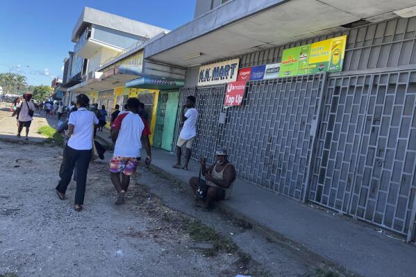People gather outside shuttered stores in Honiara, Solomon Islands, following an earthquake, Tuesday, Nov. 22, 2022. A powerful earthquake jolted the Solomon Islands Tuesday afternoon, overturning tables and sending people racing for higher ground.  (AP Photo/Charley Piringi)
