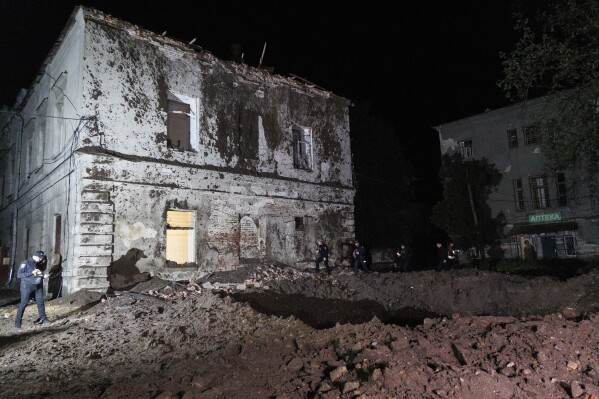 Police offices walk in front of a crater after a Russian rocket attack on mental hospital №3 in Kharkiv, Ukraine, Saturday, April 27, 2024. (AP Photo/Yakiv Liashenko)