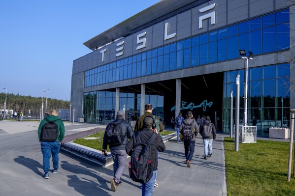 FILE - People walk to the Tesla Gigafactory for electric cars in Gruenheide near Berlin, Germany,March 13, 2024. After reporting dismal first-quarter sales, Tesla is planning to lay off about a tenth of its workforce as it tries to cut costs, multiple media outlets reported Monday. (AP Photo/Ebrahim Noroozi, File)