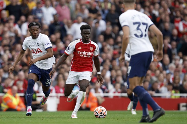 Arsenal's Bukayo Saka, center, runs with the ball during the English Premier League soccer match between Arsenal and Tottenham Hotspur at Emirates stadium in London, England, Sunday, Sept. 24, 2023. (AP Photo/David Cliff)