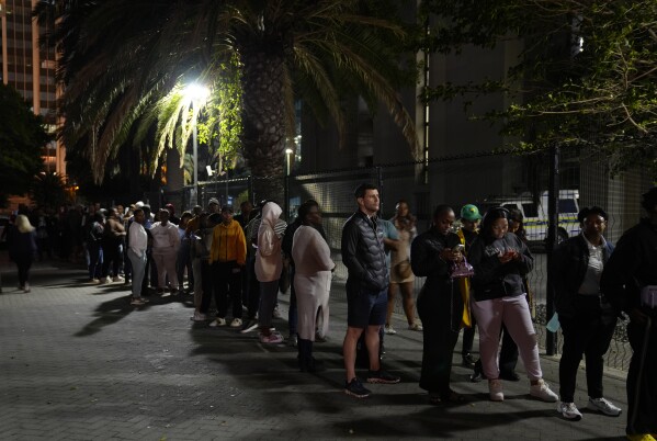 People queue after dark to vote at a polling station in Cape Town, South Africa, Wednesday May 29, 2024. South Africans cast their ballots on Wednesday at schools, community centers and large white tents set up in the open field during an election seen as the most important in their country since the end of apartheid 30 years ago.  This could place the young democracy in uncharted territory.  (AP Photo/Nardus Engelbrecht)