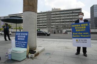 Un hombre sostiene un cartel que exige la paz en la península coreana el martes 27 de julio de 2021, cerca de la embajada estadounidense en Seúl, Corea del Sur. (AP Foto/Ahn Young-joon)