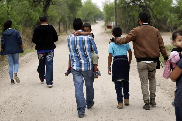 FILE - A group of migrant families walk from the Rio Grande, the river separating the U.S. and Mexico in Texas, near McAllen, Texas, March 14, 2019. A Biden administration effort to reunite children and parents who were separated under President Donald Trump's zero-tolerance border policy has made increasing progress as it nears the end of its first year. The Department of Homeland Security planned Thursday, Dec. 23, to announce that 100 children, mostly from Central America, are back with their families and about 350 more reunifications are in process after it adopted measures to enhance the program. (AP Photo/Eric Gay, File)