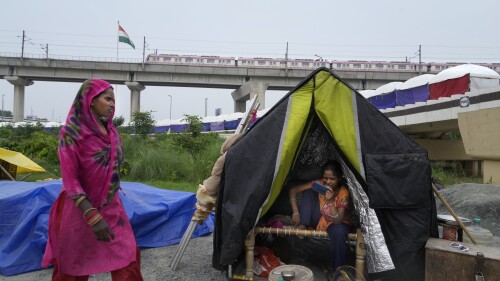 People evacuated from the flood plains of the river Yamuna rest in makeshift tents along a street in New Delhi, India, Thursday, July 13, 2023. Residential areas close to the river were flooded, submerging roads, cars and homes, leading to the evacuation of thousands of people from low-lying areas in the country's capital city. More than 100 people were killed this week after record monsoon rains led to massive waterlogging, road caves-in, collapsed homes and gridlocked traffic, officials said Thursday. (AP Photo/Manish Swarup)