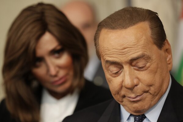 Lower Chamber Vice President Mara Carfagna looks at Forza Italia party leader Silvio Berlusconi as he talks to the press after meeting Italian President Sergio Mattarella, in Rome, Thursday, Aug. 22, 2019. President Sergio Mattarella continued receiving political leaders Thursday, to explore if a solid majority with staying power exists in Parliament for a new government that could win the required confidence vote. (AP Photo/Alessandra Tarantino)