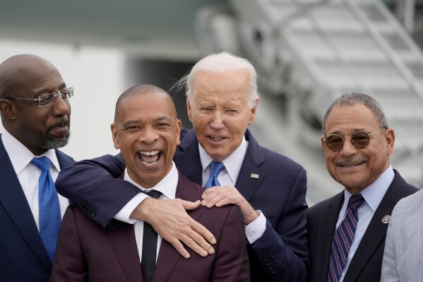 President Joe Biden, second from right, is greeted by alumni of Morehouse College including Sen. Raphael Warnock, D-Ga., from left, Marlon Kimpson, a member of the advisory committee for trade policy and negotiations in the office of the U.S. Trade Representative, and Rep. Sanford Bishop, D-Ga., upon arriving at Hartsfield-Jackson Atlanta International Airport, Saturday, May 18, 2024, in Atlanta. (AP Photo/Alex Brandon)