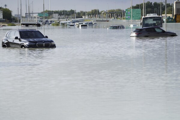 Vehículos abandonados en medio de las inundaciones que cubren una carretera en Dubai, Emiratos Árabes Unidos, 17 de abril de 2024. A medida que las nubes se acumulan, puede llover, pero en realidad no llueve a cántaros ni abruma, al menos nada parecido a lo que empapó a los Emiratos Árabes Unidos y paralizó Dubái.  (Foto AP/Jon Gambrell)