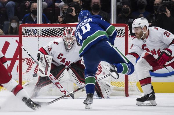 Vancouver Canucks' Elias Pettersson (40), of Sweden, scores against Carolina Hurricanes goalie Antti Raanta (32), of Finland, as Ian Cole (28) defends during the second period of an NHL hockey game in Vancouver, British Columbia, Sunday, Dec. 12, 2021. (Darryl Dyck/The Canadian Press via AP)