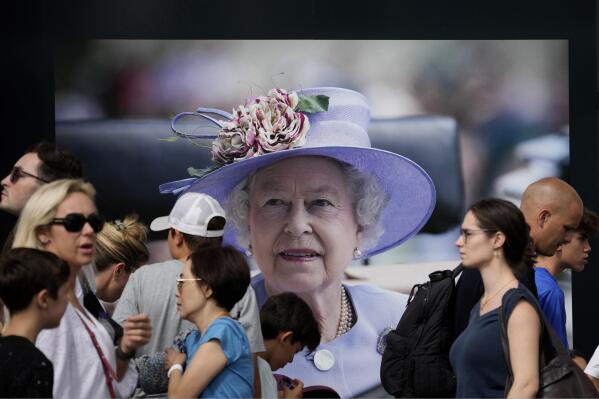 Passers by walk in front of a picture of Queen Elizabeth II, in London, Sunday, Sept. 11, 2022. Queen Elizabeth II, Britain's longest-reigning monarch and a rock of stability across much of a turbulent century, died Thursday Sept. 8, 2022, after 70 years on the throne. She was 96. (AP Photo/Christophe Ena)