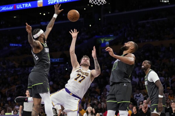 Los Angeles Lakers guard Luka Doncic (77) shoots as Minnesota Timberwolves guard Nickeil Alexander-Walker (9), center Rudy Gobert and center Naz Reid defend during the first half in Game 1 of an NBA first-round playoff series Saturday, April 19, 2025, in Los Angeles. (AP Photo/Mark J. Terrill)