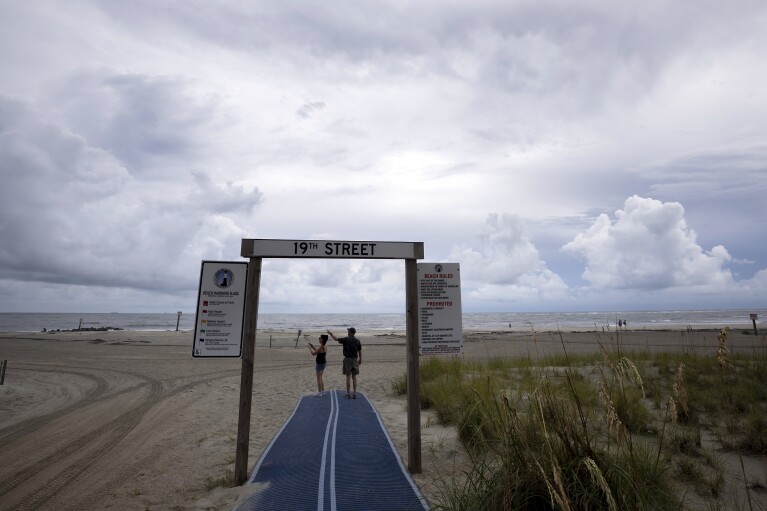 Vistors stop and take a photo of the clouds on the south end of Tybee Island, Ga., ahead of Hurricane Idalia on Tuesday, Aug., 29, 2023. Idalia strengthened into a hurricane Tuesday and barreled toward Florida's Gulf Coast. (Stephen B. Morton /Atlanta Journal-Constitution via AP)