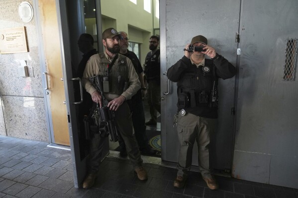 Law enforcement watch protesters at the U.S. Department of Justice Federal Bureau of Prisons after federal immigration authorities conducted an operation on Friday, June 6, 2025, in Los Angeles. (AP Photo/Jae C. Hong)