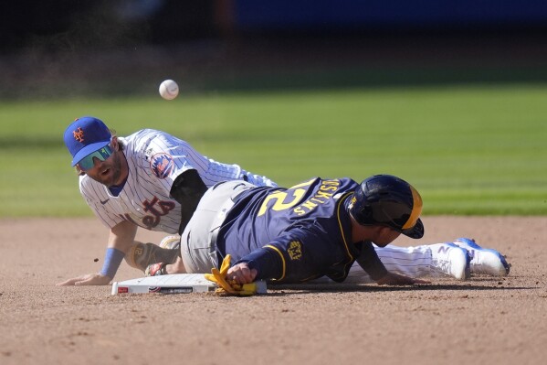 New York Mets' Jeff McNeil (1) loses control of the ball as Milwaukee Brewers' Rhys Hoskins (12) slides into him during the eighth inning of a baseball game Friday, March 29, 2024, in New York. (AP Photo/Frank Franklin II)