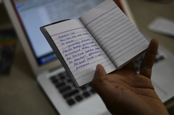 CORRECTS JOURNALIST'S FIRST NAME - Indian journalist Sidhique Kappan at his home in Kerala, India, shows notes from the diary he kept in prison, April 1, 2024. He was charged in 2020 on allegations of inciting violence while trying to report on a government clampdown in the northern Uttar Pradesh state ruled by the party of Prime Minister Narendra Modi. The time it takes to defend himself has made it difficult to work to support his family. (AP Photo/R S Iyer)