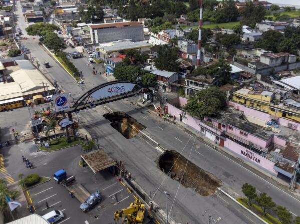 A sinkhole is exposed on the main road in Villa Nueva, Guatemala, Sunday, Sept. 25, 2022. Rescuers are searching for people who are believed to have fallen into the sinkhole while driving their vehicle, while four others were rescued alive from the scene on Saturday night, according to authorities. (AP Photo/Moises Castillo)