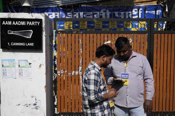 Voluntários do Partido Aam Aadmi (AAP) Verifique os resultados em dispositivos móveis fora de seu escritório do partido, pois os votos estão sendo contados nas eleições do estado de Delhi em Nova Délhi, Índia, sábado, 8 de fevereiro de 2025. (AP Photo/Manish Swarup)