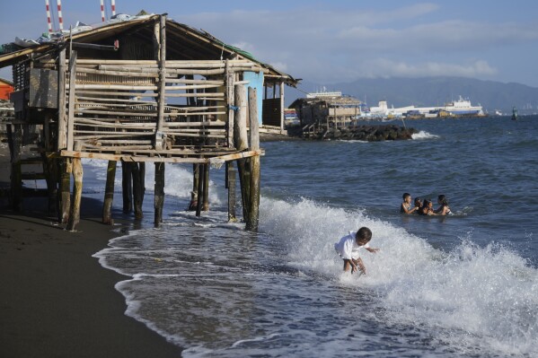 Children play in Santa Clara near a liquified natural gas power plant in Batangas province, Philippines on Tuesday, Aug. 8, 2023. The Philippines is seeing one of the world's biggest buildouts of natural gas infrastructure. But the buildout raises serious questions about the health of nearby coral reefs and fishing communities. (AP Photo/Aaron Favila)