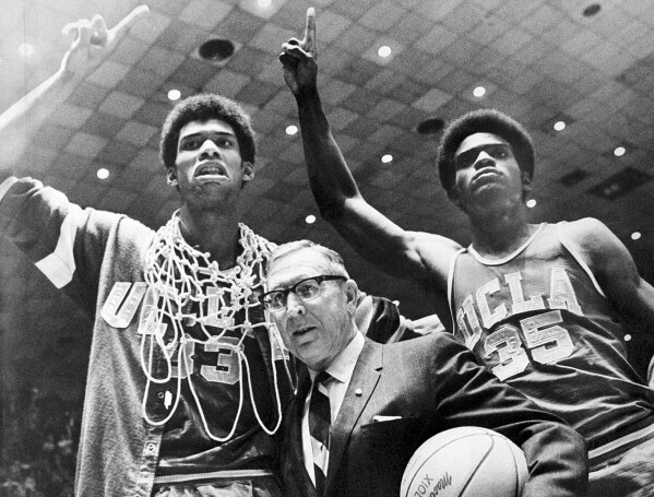 FILE - Sidney Wicks, right, and Lew Alcindor, left, are wrapped in basket ropes next to UCLA coach John Wooden after the UCLA team defeated Purdue 92-72 to win the NCAA college basketball title for the third consecutive year in Louisville, Ky. .  , 24 March 1969.  (AP Photo/File)