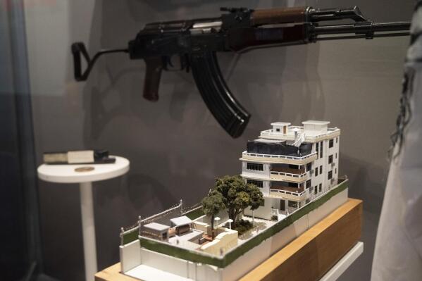 A model of the house where a precision counterterrorism operation killed al-Qaida's leader Ayman al-Zawahri is displayed below a rifle used by Michael Spann, the first American killed in Afghanistan, in the refurbished museum at the Central Intelligence Agency headquarters building in Langley, Va., on Saturday, Sept. 24, 2022. (AP Photo/Kevin Wolf)