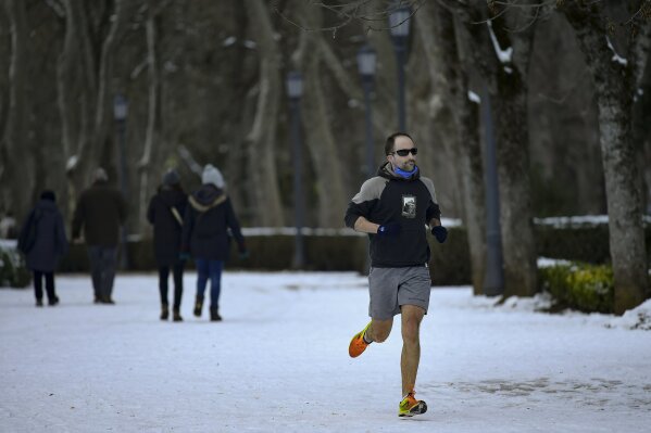 A man jog, after the recent snow fall, in Pamplona, northern Spain, Sunday, Jan. 10, 2021. Emergency crews in central Spain have cleared 500 roads and rescued over 1,500 people stranded in vehicles as the country shovels out of its worst snowstorm in recent memory. (AP Photo/Alvaro Barrientos)