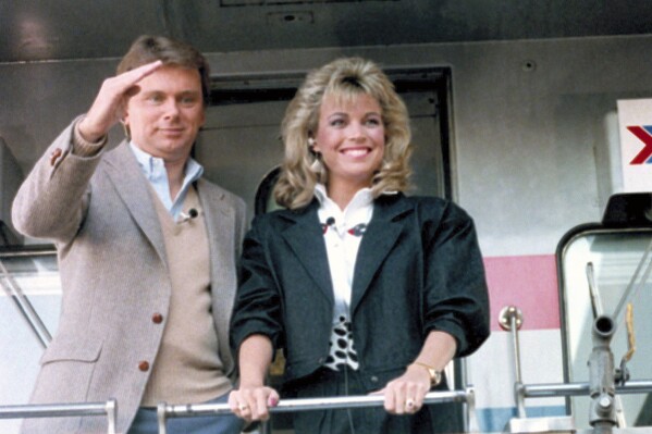 FILE - Pat Sajak, left, and Vanna White appear aboard the Wheel of Fortune Express in Miami on Feb. 12, 1987 to tour 33 cities from Miami to Washington, DC. (AP Photo/Judy Sloan, File)