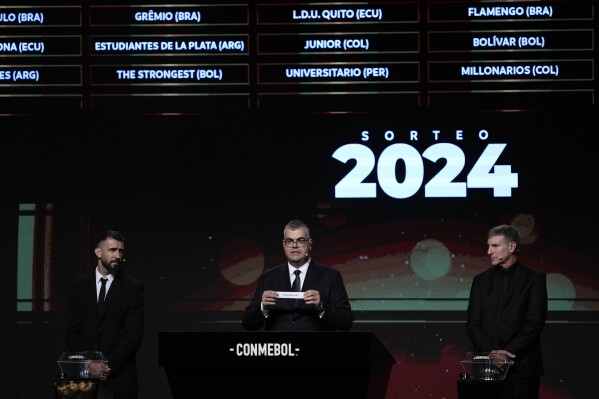 Competitions Director of Conmebol Frederico Nantes, center, holds a paper with the name of Argentina's Rosario Central during the Copa Libertadores draw in Luque, Paraguay, Monday, March 18, 2024. (AP Photo/Jorge Saenz)