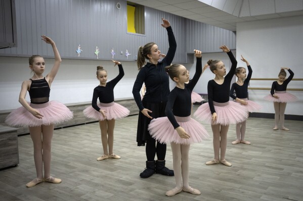 A ballet coach teaches girls in a ballet studio in a bomb shelter in Kharkiv, Ukraine, Monday, March 18, 2024. In northeast Ukraine, a dance studio that doubles as a bomb shelter is an escape from the horrors of war for about 20 young girls. The Princess Ballet Studio in Kharkiv is a spartan, windowless room, but practicing underground means they can dance through the almost hourly air raid alerts. (AP Photo/Efrem Lukatsky)
