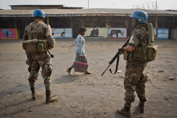 FILE - A Congolese women walks past United Nations peacekeepers from Uruguay as they stand guard on a street in Goma, eastern Congo, Friday, July 13, 2012. The Security Council on Tuesday, Dec. 19, 2023, voted unanimously to start the withdrawal of the U.N. peacekeeping force from Congo before the end of the year as the conflict-ridden country prepares to elect its next president on Wednesday. (AP Photo/Marc Hofer, File)