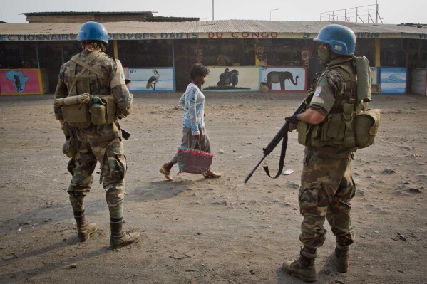 FILE - A Congolese women walks past United Nations peacekeepers from Uruguay as they stand guard on a street in Goma, eastern Congo, Friday, July 13, 2012. The Security Council on Tuesday, Dec. 19, 2023, voted unanimously to start the withdrawal of the U.N. peacekeeping force from Congo before the end of the year as the conflict-ridden country prepares to elect its next president on Wednesday. (AP Photo/Marc Hofer, File)