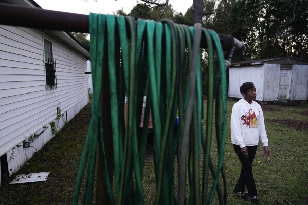 Angela Adams stands in the backyard of her home of 30 years on Tuesday, Dec. 5, 2023, in the Alabama Village neighborhood, in Prichard, Ala. There is talk of seizing residents' property and paying them to move to help stem the city's water loss and create opportunities for redevelopment. (AP Photo/Brynn Anderson)