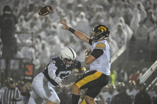 Penn State defensive tackle Jordan van den Berg (52) pressures Iowa quarterback Deacon Hill (10) during the second half of an NCAA college football game as rain falls on Saturday, Sept. 23, 2023, in State College, Pa. (AP Photo/Barry Reeger)