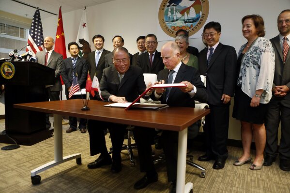 FILE - In this Sept. 13, 2014, file photo, California Gov. Jerry Brown, front right, and China's National Development and Reform Commission Vice Chairman Xie Zhenhua, front left, sign an agreement to boost bilateral cooperation on climate change during a news conference at the Bay Area Council, in San Francisco. As tensions between China and the United States ratchet up, former California Gov. Jerry Brown sees a way to bring together the world's largest carbon emitter and a U.S. state that's leading the way in energy standards: climate change. (AP Photo/Beck Diefenbach,file)