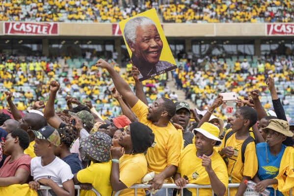 African National Congress supporters, one holding a portrait of Nelson Mandela, gather at the Mose Mabhida stadium in Durban, South Africa, Saturday, Feb. 24, 2024, for their national manifesto launch in anticipation of the 2024 general elections. (AP Photo/Jerome Delay)