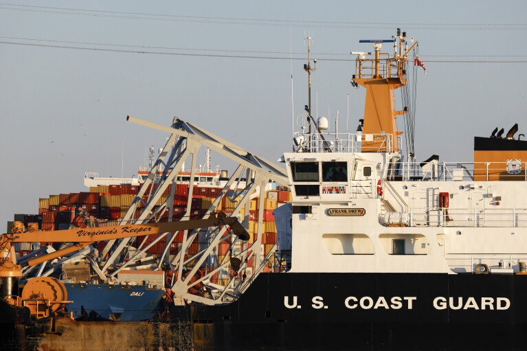 A Coast Guard coastal buoy tender passes by as wreckage of the Francis Scott Key Bridge rests on the container ship Dali, Saturday, March 30, 2024, in Baltimore. (AP Photo/Julia Nikhinson)