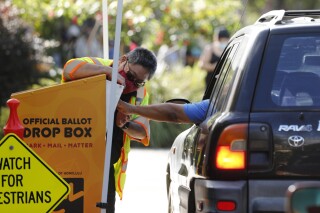 FILE - In this Nov. 3, 2020, file photo, an attendant helps a driver drop off a ballot on Election Day in Honolulu. Social media users are misrepresenting the status of a bill that could disqualify Trump from the ballot in Hawaii during the 2024 race. (AP Photo/Marco Garcia, File)