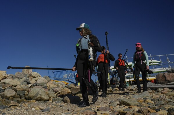 Erin Greene, left, owner of Sup North, leads a tour group down to the shoreline, Thursday, Aug. 8, 2024, in Churchill, Manitoba. (AP Photo/Joshua A. Bickel)