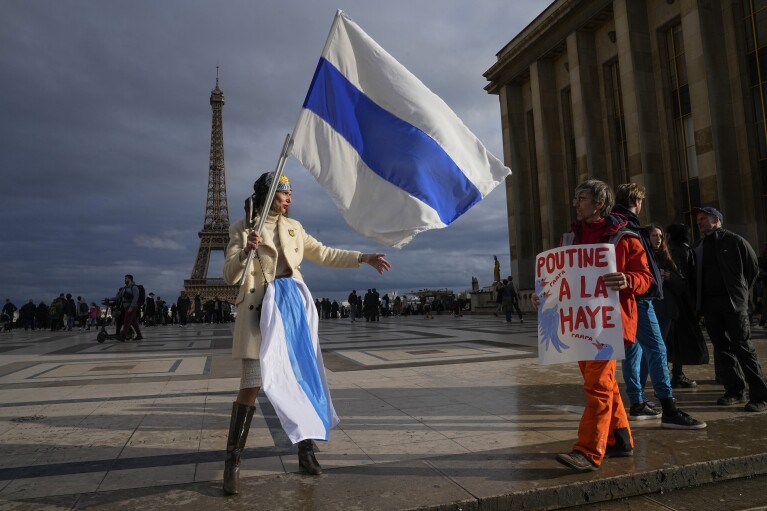 An activist with the Russian Liberties Association waves an opposition flag as she protests against President Vladimir Putin at the Trocadero Plaza near the Eiffel Tower in Paris, Sunday, March 17, 2024. Russians at home and abroad are heading to the polls for a presidential election that is certain to extend President Vladimir Putin's rule after... Suppression of opposition.  (AP Photo/Michel Euler)