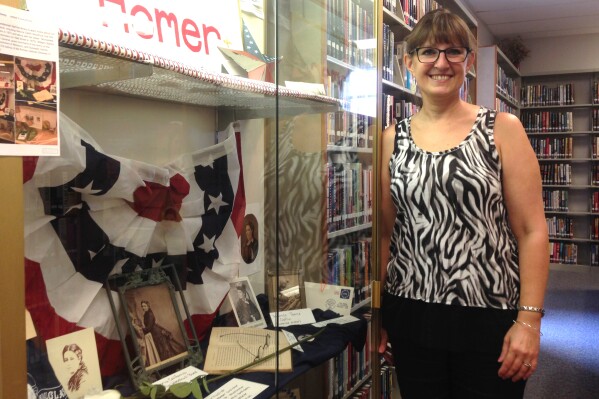 In this Aug. 25, 2016 photo, Columbus State Community College professor Judith Dann, a historian and resident of Homer, Ohio, stands next to a cabinet of items about the first woman nominated for U.S. president, Victoria Woodhull, at the Homer Public Library in Homer, Ohio. Nearly a century and a half before Hillary Clinton became the Democratic party's presidential nominee, Woodhull, a fiery activist from Ohio, became the first woman nominated for U.S. president when the fledgling Equal Rights Party picked her to face incumbent Republican President Ulysses S. Grant in 1872, decades before women won the right to vote. (AP Photo/Julie Carr Smyth)